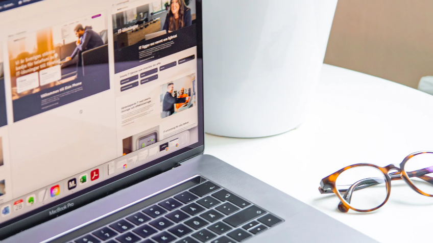 Öppen laptop och glasögon på ett skrivbord